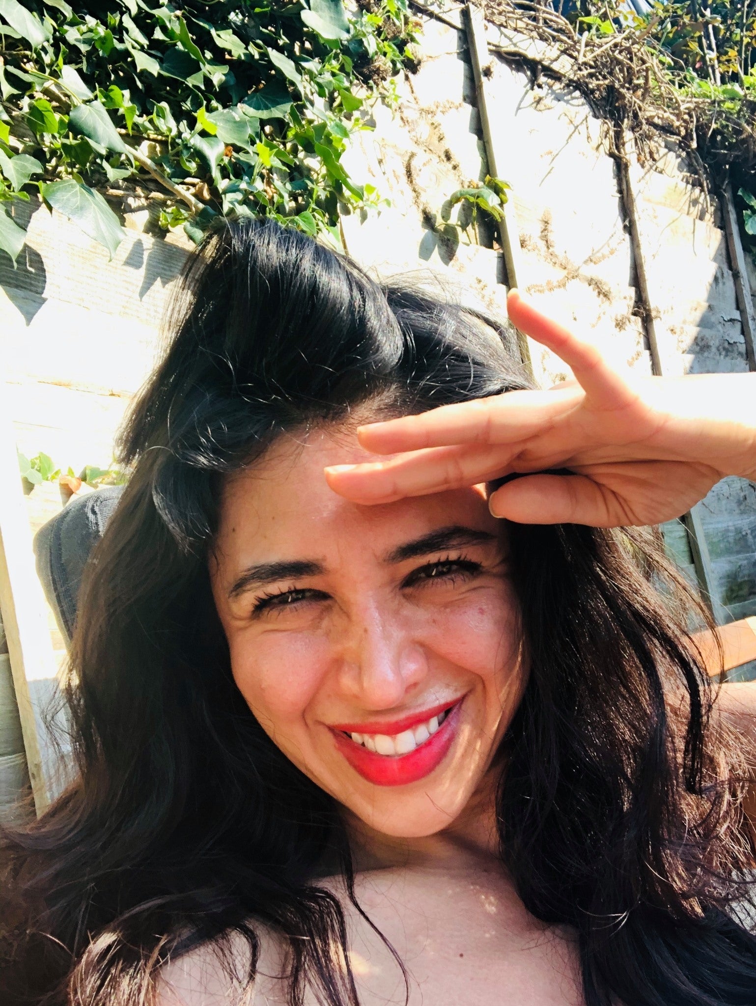Picture of Sherry, the Founder smiling looking nito the camrea shelding her eyes from the sun 